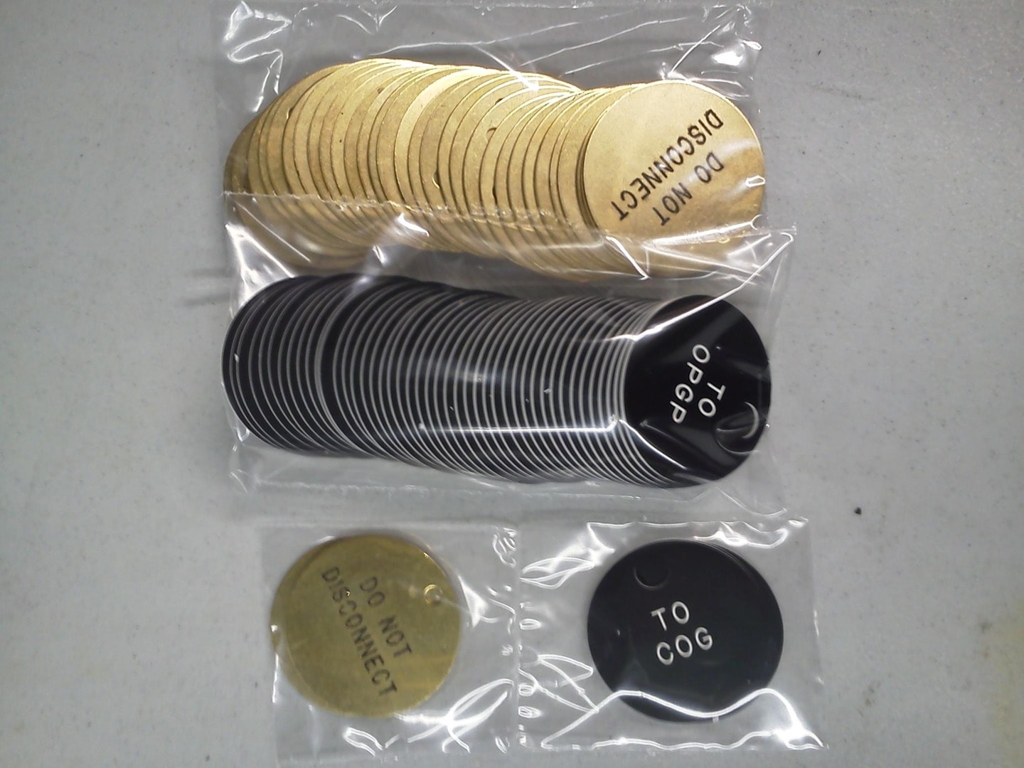 Packaged brass and black phenolic engraved valve tags — Do Not Disconnect and To COG