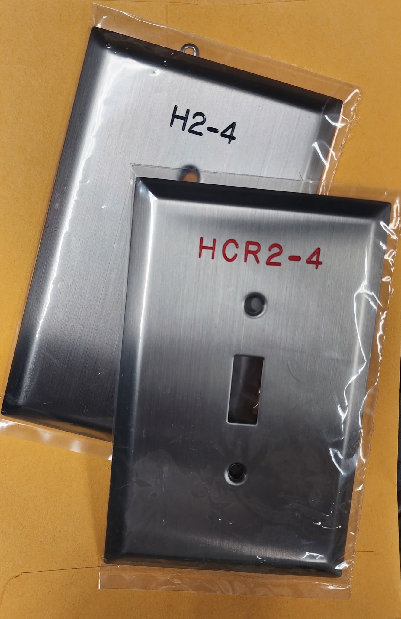 Engraved stainless steel switch plates H2-4 and HCR2-4 in packaging