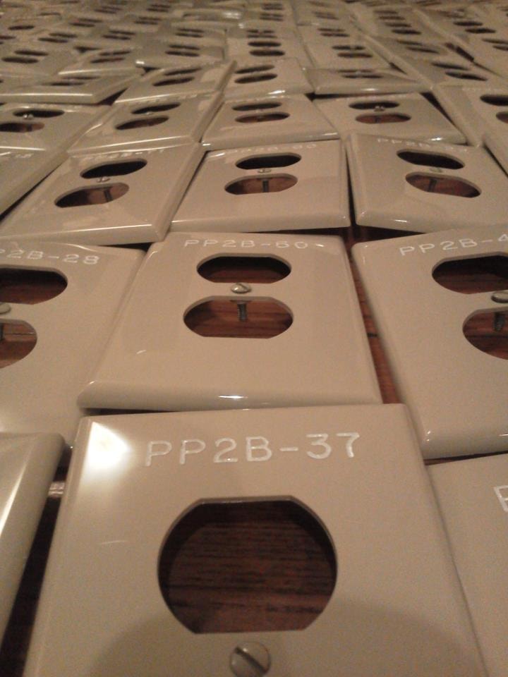 Large batch of engraved beige plastic duplex outlet plates labeled PP2B series
